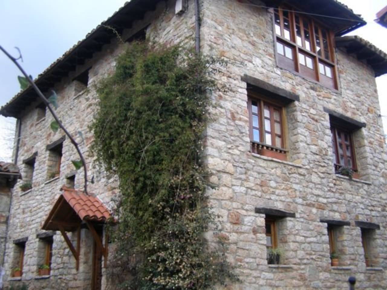 Casa en piedra y madera con varias edificaciones auxiliares y jardín