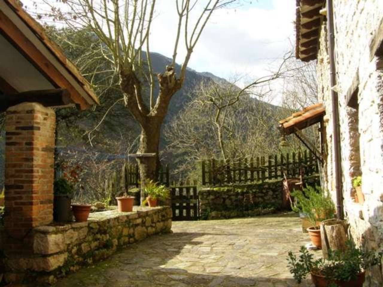 Casa en piedra y madera con varias edificaciones auxiliares y jardín
