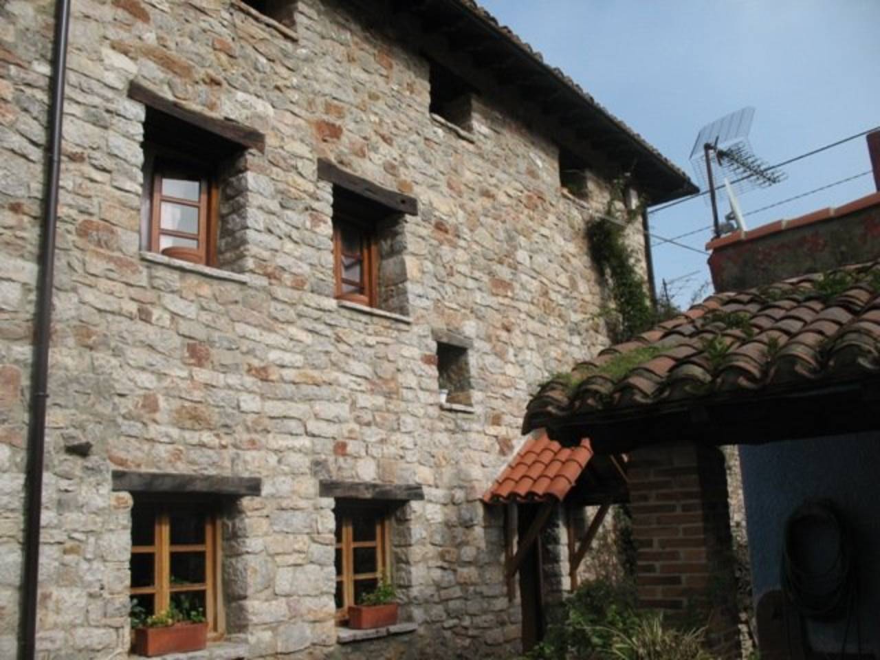 Casa en piedra y madera con varias edificaciones auxiliares y jardín